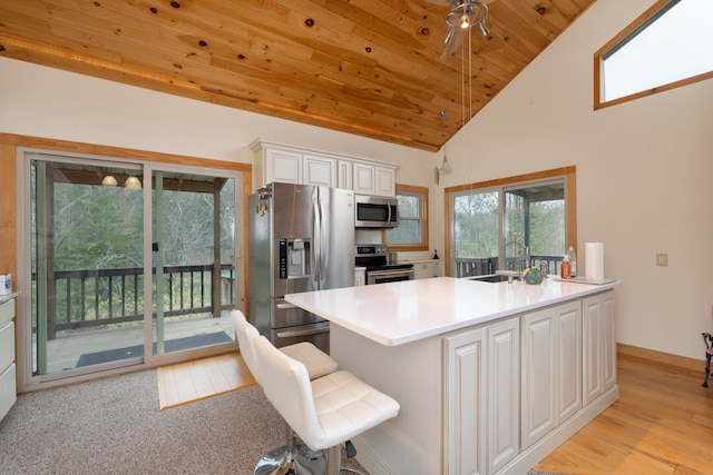 kitchen with appliances with stainless steel finishes, wood ceiling, sink, white cabinets, and light hardwood / wood-style floors