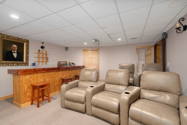 carpeted cinema room with a paneled ceiling and bar area