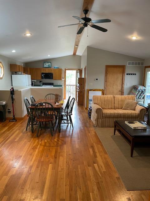 dining room with light hardwood / wood-style floors, ceiling fan, and vaulted ceiling