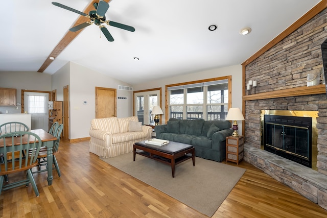 living room featuring light hardwood / wood-style flooring, vaulted ceiling with beams, plenty of natural light, and a fireplace