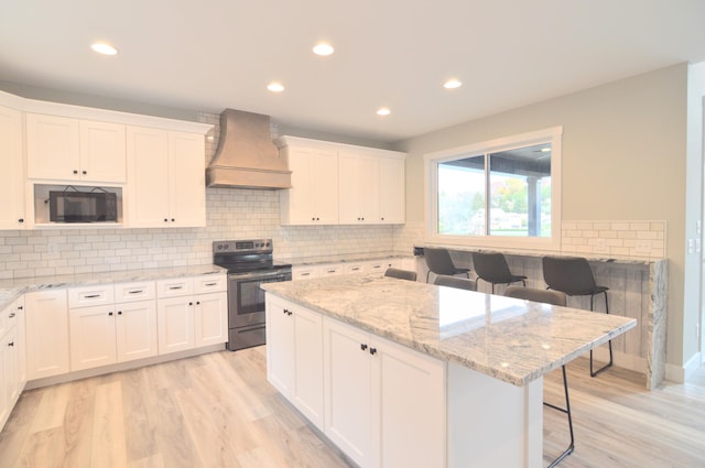 465 Cedar Hill Dr, Williamstown, KY 41097 - kitchen featuring stainless steel electric stove, custom exhaust hood, black microwave, light wood-style flooring, and white cabinetry