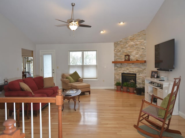 living room with light hardwood / wood-style floors, a fireplace, ceiling fan, and lofted ceiling