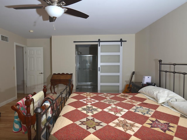 bedroom with a barn door, ceiling fan, and hardwood / wood-style flooring