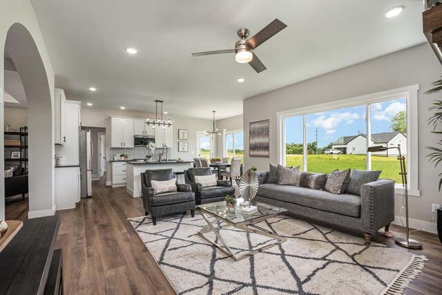 living room featuring dark hardwood / wood-style floors, plenty of natural light, and ceiling fan with notable chandelier