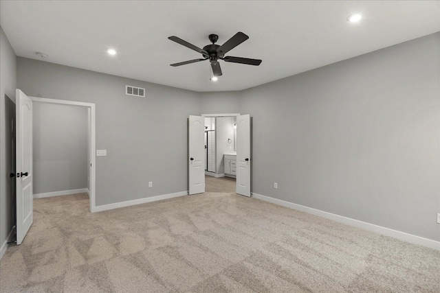 unfurnished bedroom with ensuite bathroom, light carpet, and ceiling fan