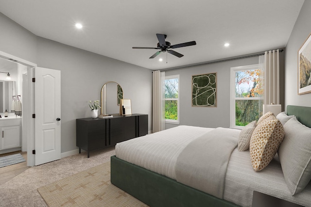 bedroom with connected bathroom, ceiling fan, multiple windows, and light wood-type flooring