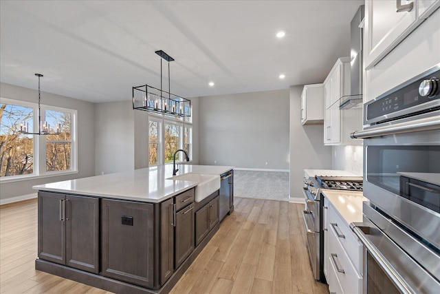 kitchen with white cabinets, sink, a wealth of natural light, a notable chandelier, and stainless steel appliances