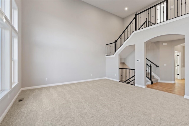 unfurnished living room with carpet and a high ceiling