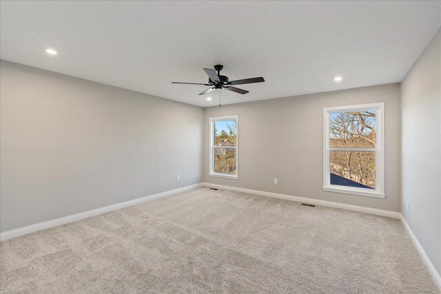 carpeted spare room featuring plenty of natural light and ceiling fan