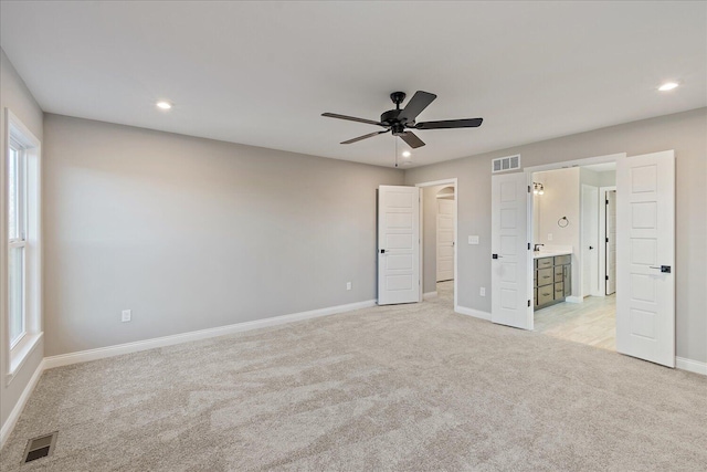 unfurnished bedroom with light carpet, ensuite bath, and ceiling fan