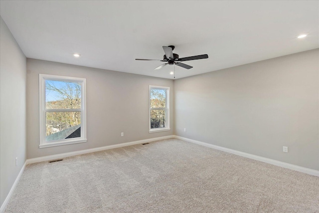 spare room featuring ceiling fan, light carpet, and a wealth of natural light