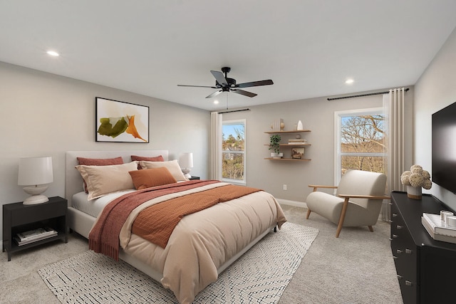 carpeted bedroom featuring multiple windows and ceiling fan