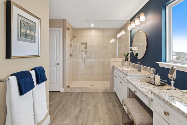 bathroom with vanity with extensive cabinet space, plenty of natural light, and a tile shower