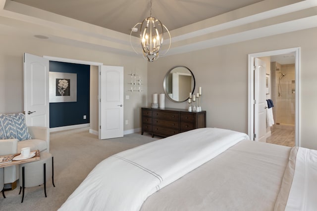 carpeted bedroom featuring a tray ceiling, ensuite bathroom, and a chandelier