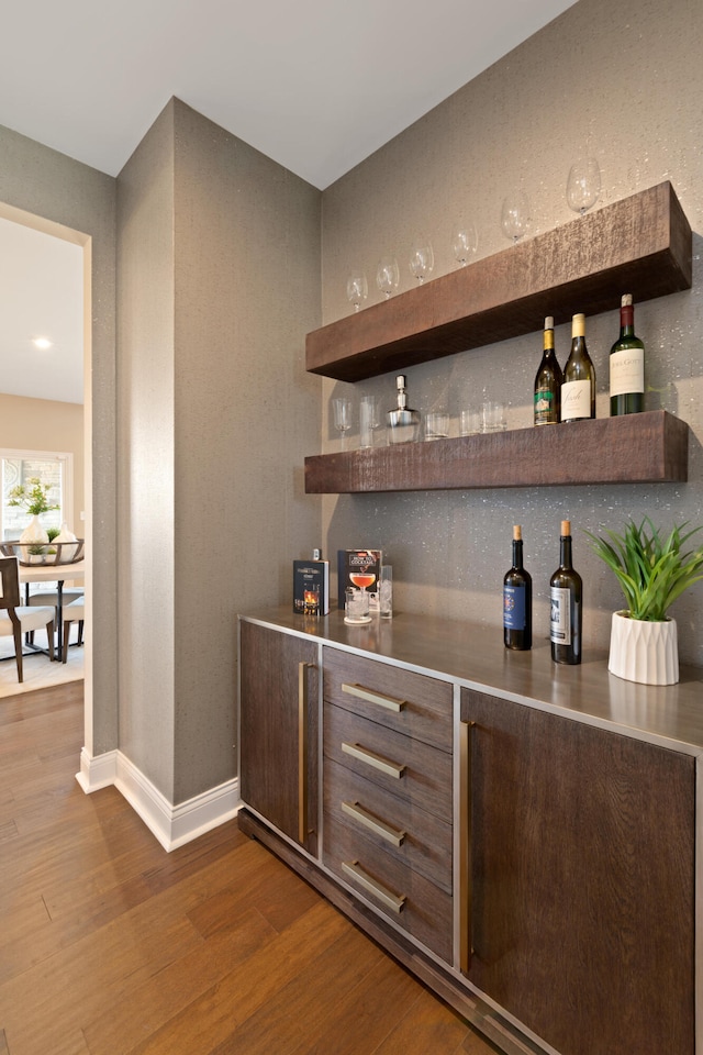 bar with hardwood / wood-style floors and stainless steel counters