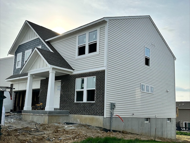 view of front facade with roof with shingles, cooling unit, and brick siding