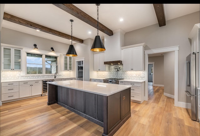 kitchen with white cabinets, beam ceiling, tasteful backsplash, and light wood-type flooring