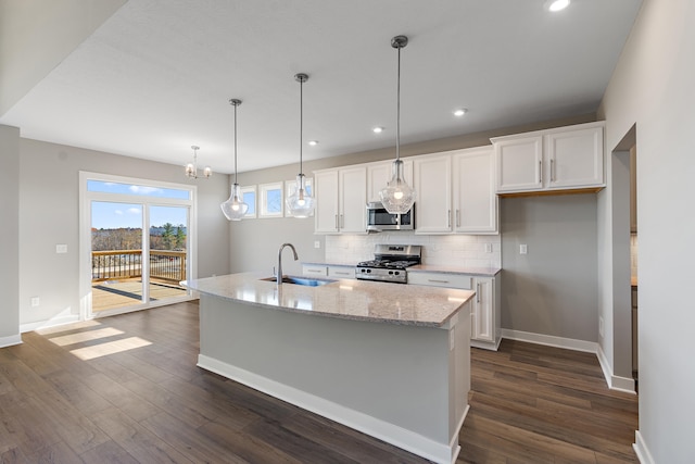 kitchen with white cabinetry, sink, stainless steel appliances, dark hardwood / wood-style floors, and an island with sink