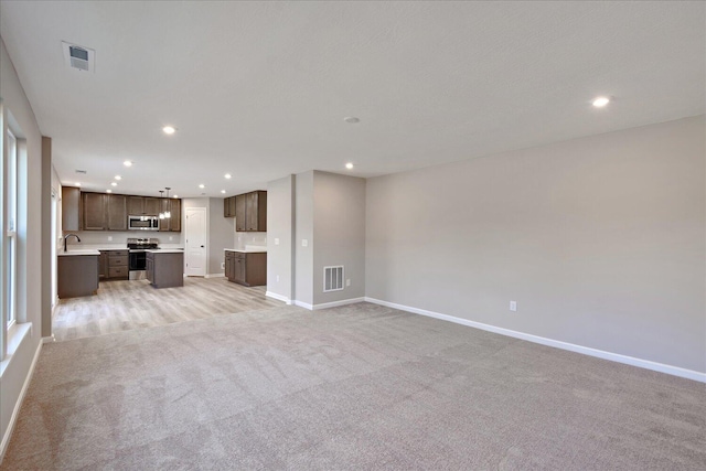 unfurnished living room with light carpet and sink