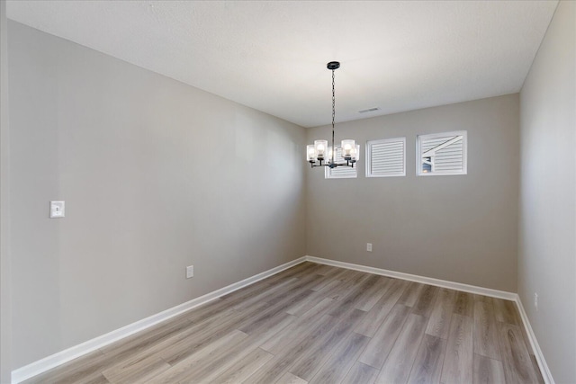 spare room featuring light hardwood / wood-style flooring and an inviting chandelier