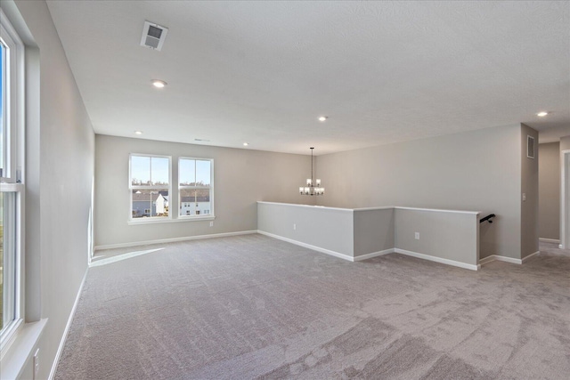 unfurnished room with light colored carpet and an inviting chandelier