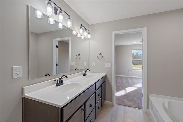 bathroom with a washtub, vanity, and wood-type flooring