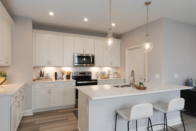 kitchen with backsplash, white cabinets, a sink, and stainless steel appliances