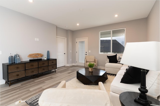 living room with recessed lighting, baseboards, and light wood-type flooring