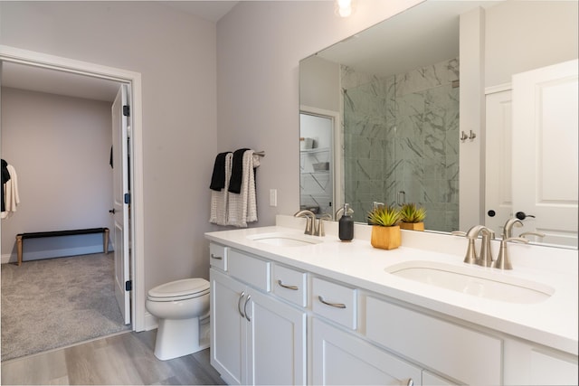 bathroom with toilet, a sink, a stall shower, and double vanity