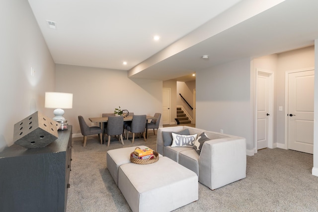 living room featuring baseboards, visible vents, stairway, and light colored carpet