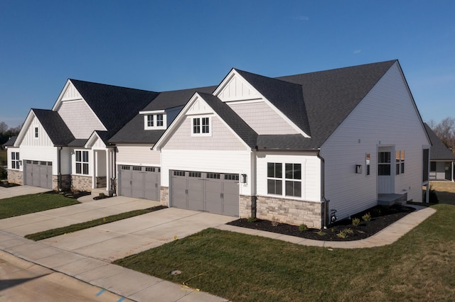 view of front of property featuring concrete driveway, an attached garage, stone siding, board and batten siding, and a front lawn