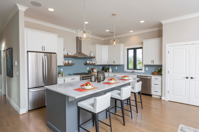 kitchen with wall chimney range hood, tasteful backsplash, hardwood / wood-style floors, a center island, and appliances with stainless steel finishes