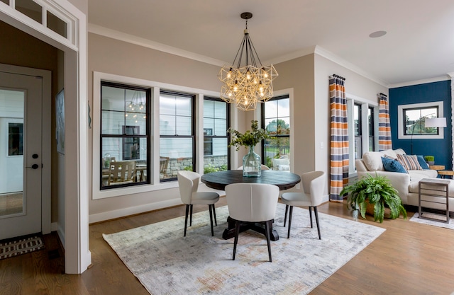 dining space with an inviting chandelier, crown molding, and wood-type flooring