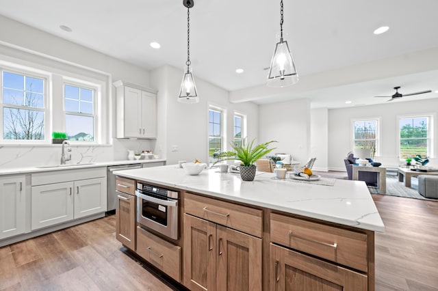 kitchen featuring pendant lighting, white cabinets, sink, appliances with stainless steel finishes, and a kitchen island