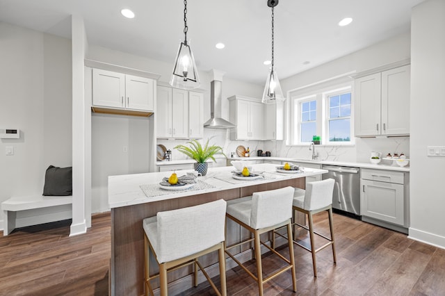 kitchen with dishwasher, white cabinets, a kitchen island, and wall chimney range hood