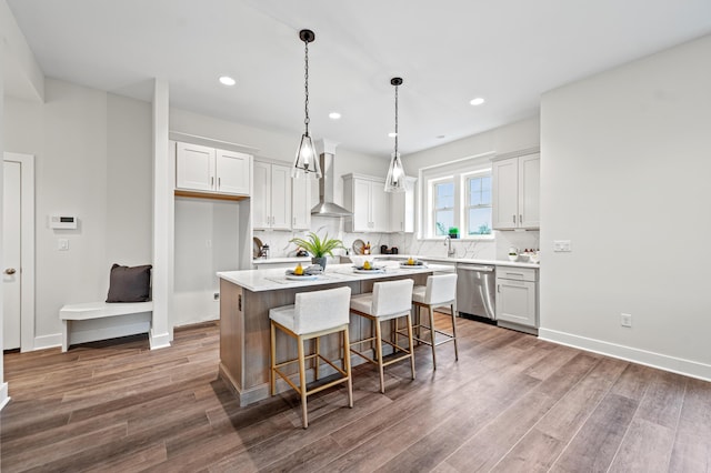 kitchen with a center island, white cabinetry, stainless steel dishwasher, and wall chimney exhaust hood