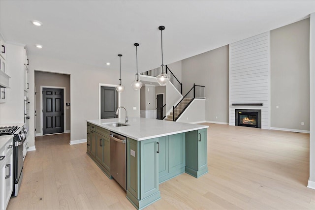 kitchen with range with gas cooktop, dishwasher, hanging light fixtures, a kitchen island with sink, and a fireplace