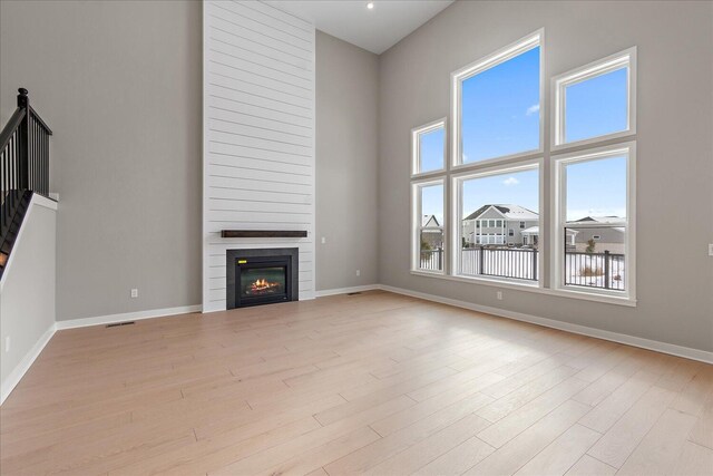 unfurnished living room with a towering ceiling and light hardwood / wood-style floors