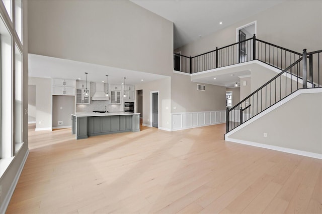 unfurnished living room featuring a high ceiling and light hardwood / wood-style flooring