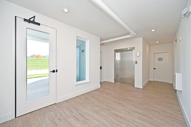 entrance foyer featuring radiator, elevator, and light hardwood / wood-style floors