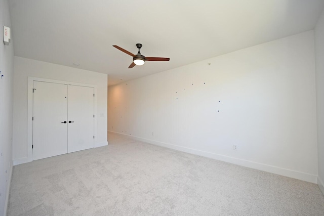 unfurnished bedroom featuring light colored carpet, a closet, and ceiling fan