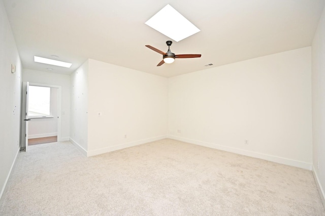 spare room with light colored carpet, ceiling fan, and a skylight