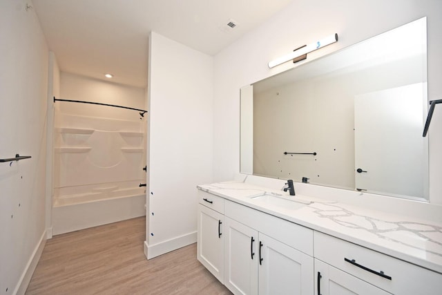 bathroom featuring hardwood / wood-style flooring, vanity, and bathing tub / shower combination