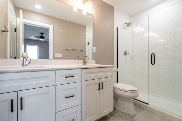 bathroom with ceiling fan, tile patterned floors, toilet, vanity, and a shower with shower door