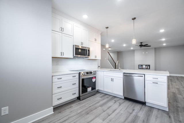 kitchen featuring white cabinets, appliances with stainless steel finishes, kitchen peninsula, and ceiling fan