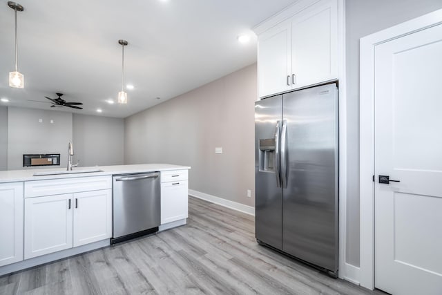 kitchen featuring white cabinetry, sink, ceiling fan, hanging light fixtures, and stainless steel appliances