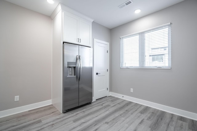 kitchen featuring white cabinets, stainless steel fridge with ice dispenser, and light wood-type flooring