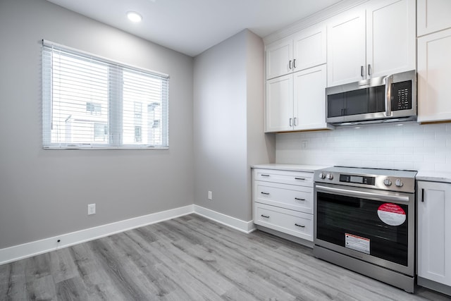 kitchen with decorative backsplash, white cabinets, and stainless steel appliances