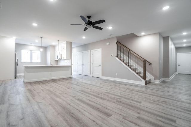 unfurnished living room with ceiling fan, sink, and light hardwood / wood-style flooring