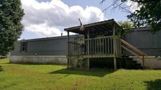 back of house with a wooden deck and a lawn